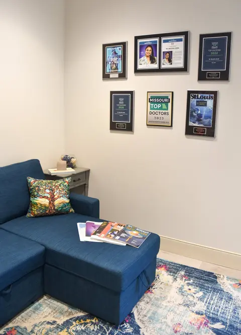 Patient lounge with navy sofa, tree-of-life pillows, and award wall